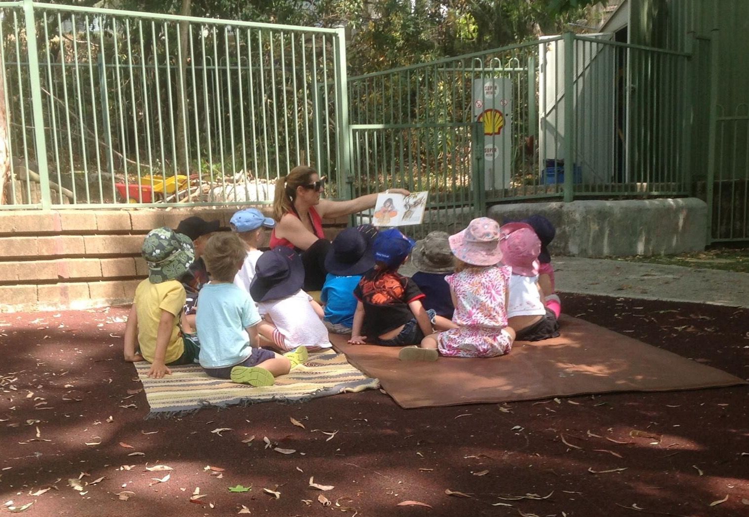 An educator reading a story to children outdoors